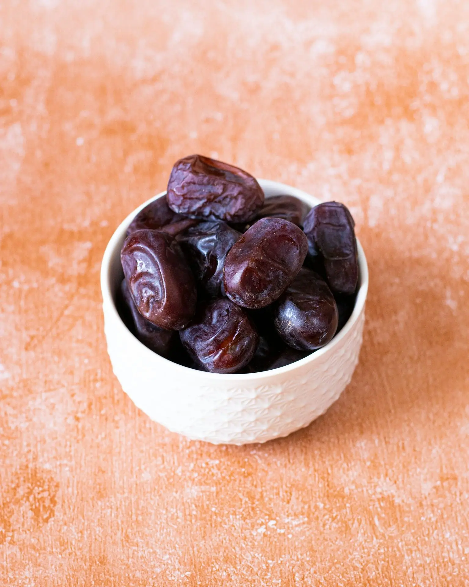a white bowl filled with raisins on top of a wooden table